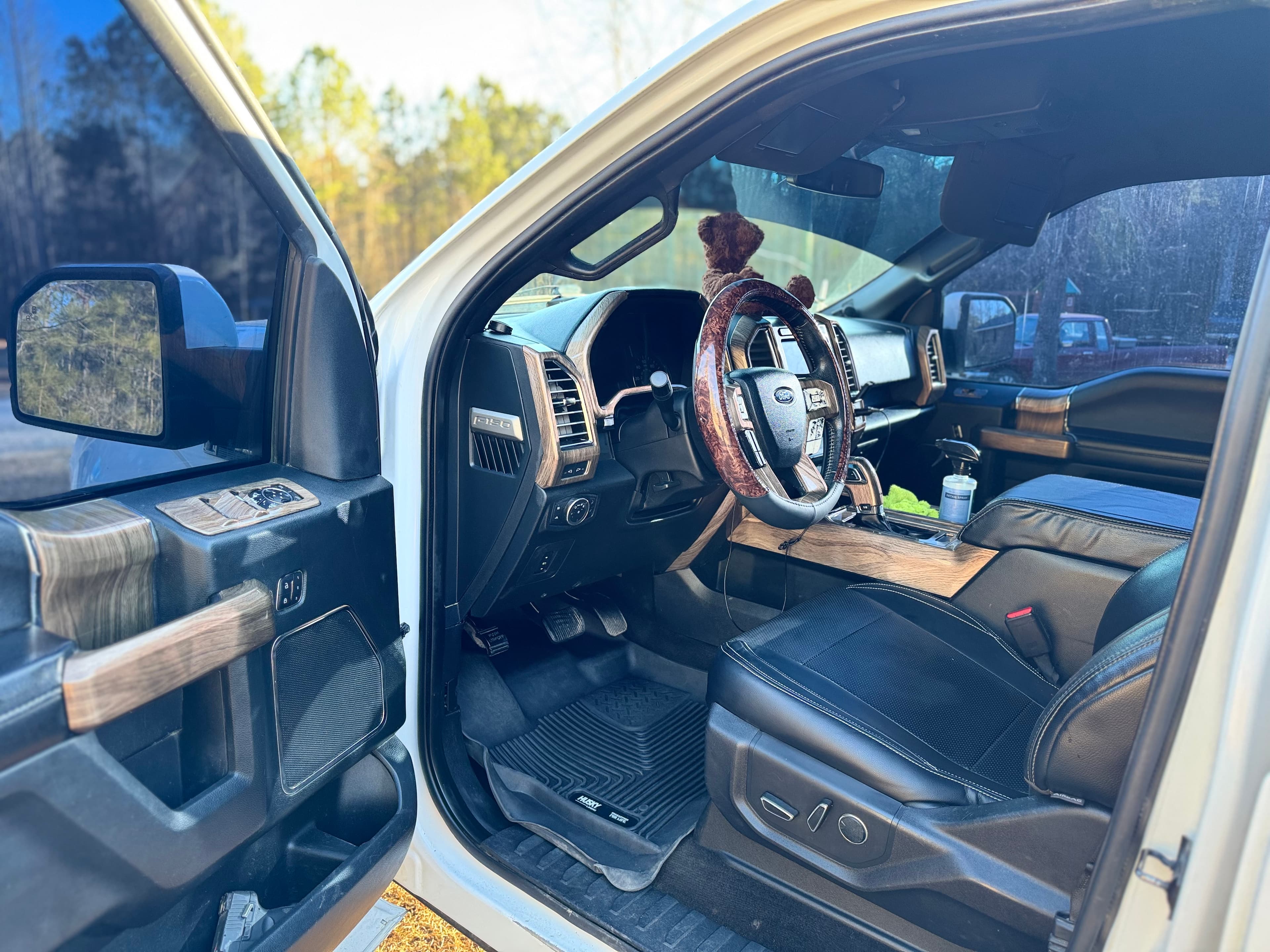 Interior view of a Ford F-150 with black leather seats and wood grain trim.