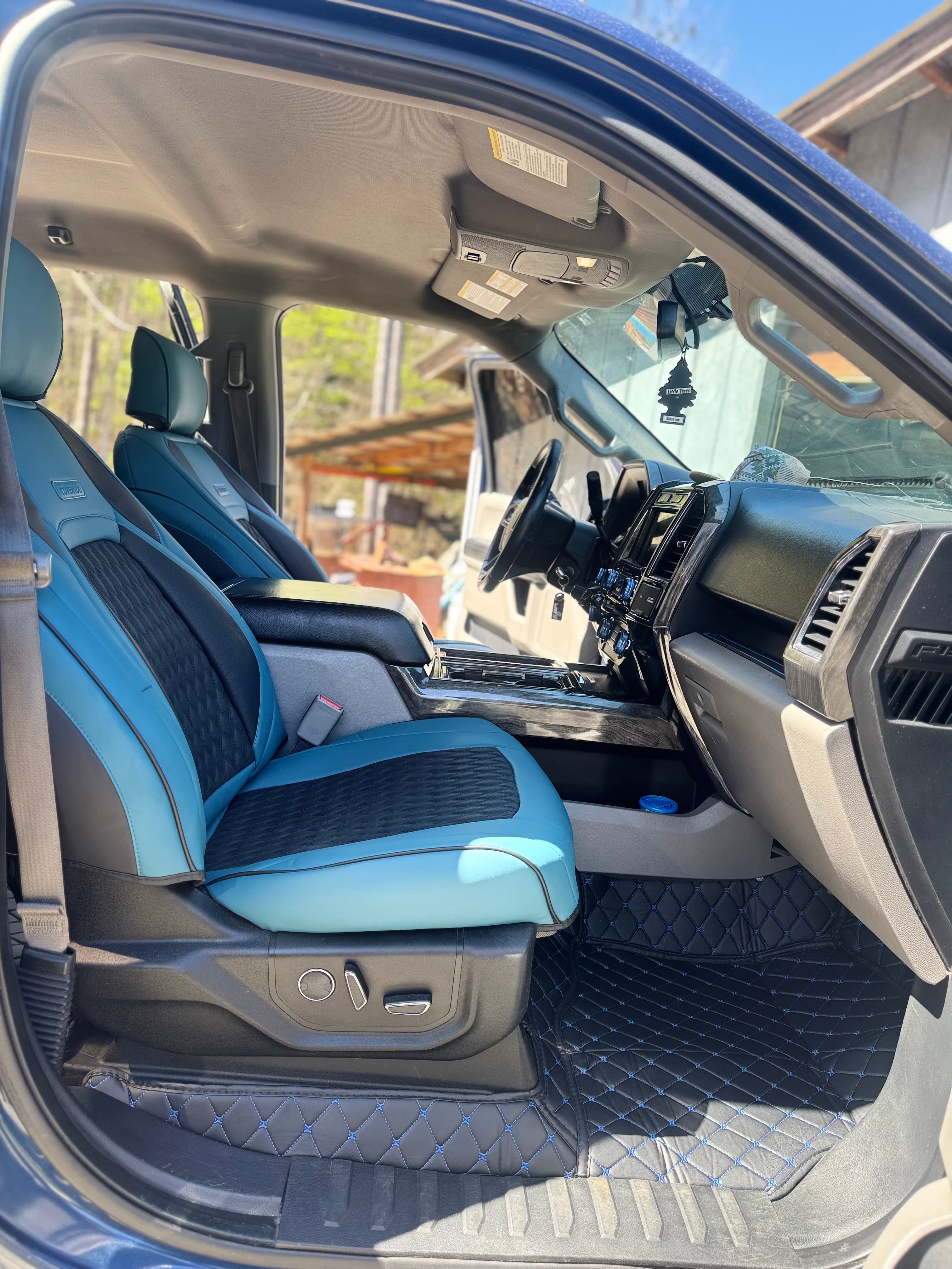 Silverado truck interior with custom blue and black seat covers and matching diamond-stitched floor mats.